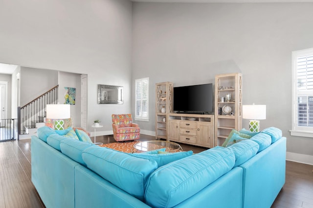 living area with plenty of natural light, stairway, baseboards, and wood finished floors