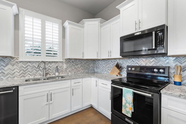 kitchen with light stone counters, stainless steel appliances, tasteful backsplash, white cabinets, and a sink