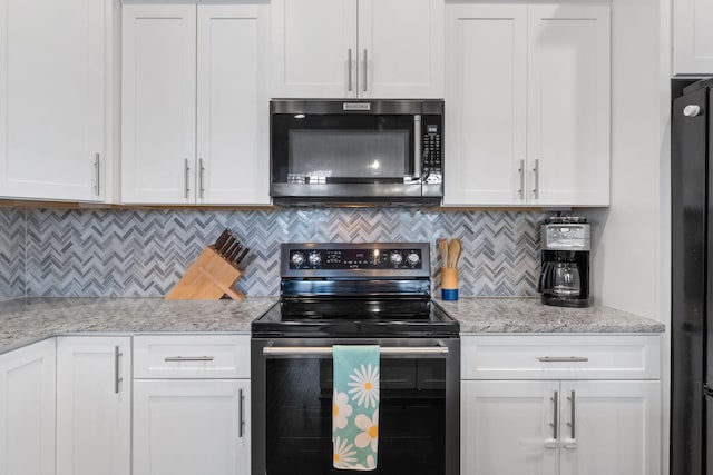 kitchen with freestanding refrigerator, stainless steel microwave, electric range oven, and white cabinetry