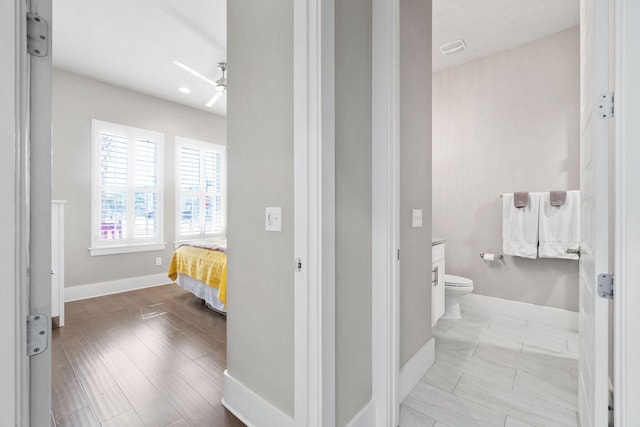 bathroom featuring toilet, baseboards, a ceiling fan, and wood finished floors