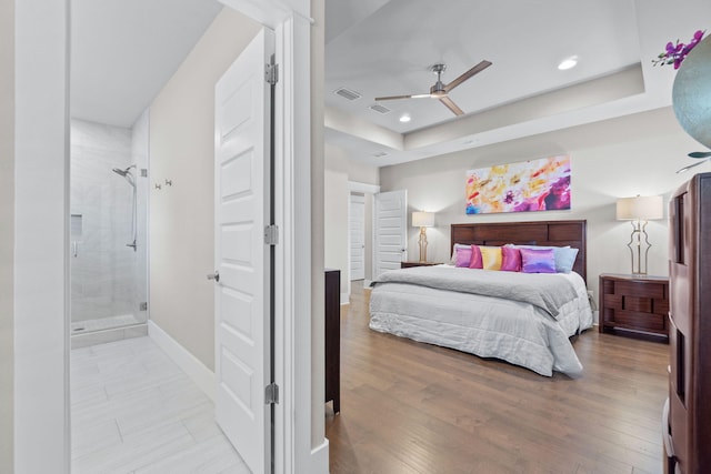 bedroom with light wood finished floors, a raised ceiling, visible vents, and recessed lighting