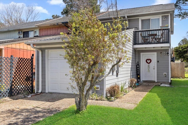 view of front facade with a front yard, a balcony, fence, driveway, and roof with shingles