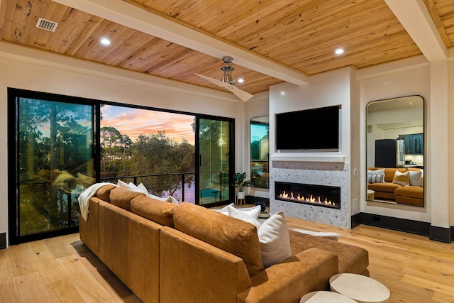 living room featuring beam ceiling, wood ceiling, light wood-type flooring, and a lit fireplace