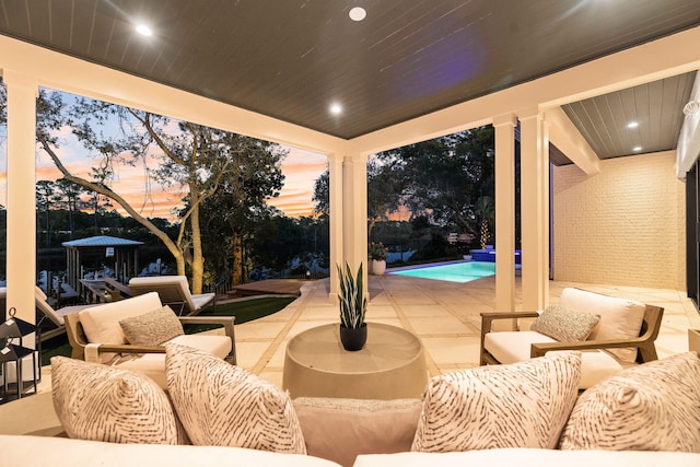 patio terrace at dusk with outdoor lounge area and an outdoor pool