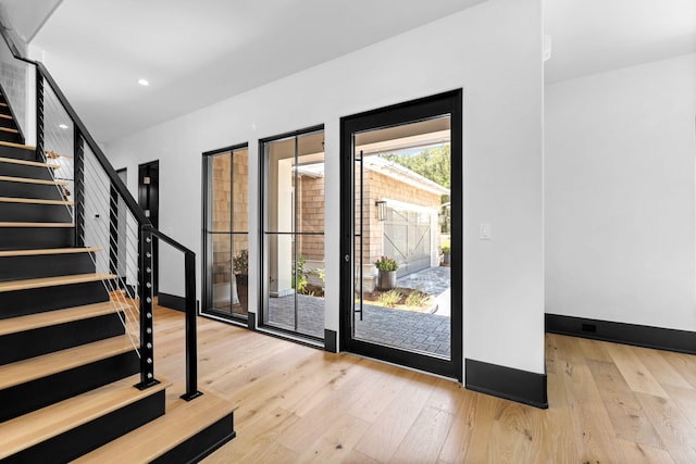 doorway featuring hardwood / wood-style floors, stairs, recessed lighting, and baseboards