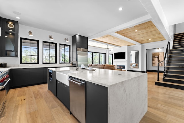 kitchen with stainless steel appliances, dark cabinets, and light wood-style flooring