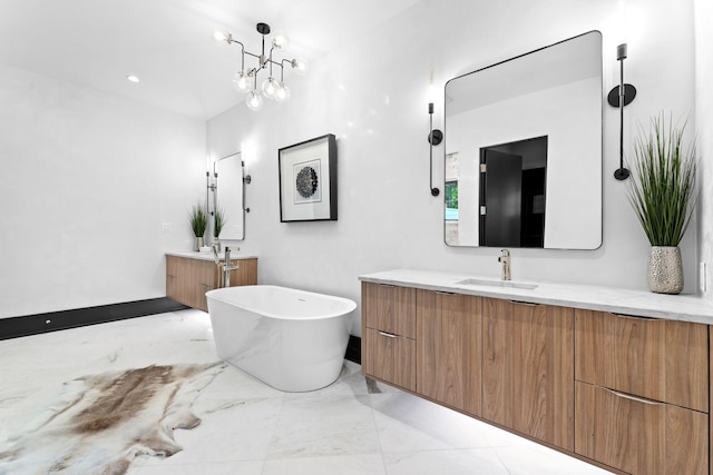 bathroom featuring two vanities, marble finish floor, a sink, an inviting chandelier, and a soaking tub