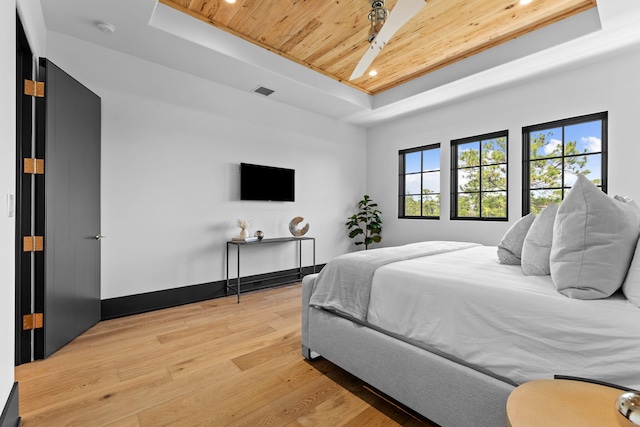 bedroom with wooden ceiling, light wood-type flooring, a raised ceiling, and baseboards