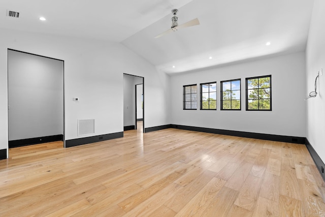 empty room with visible vents, light wood-style flooring, baseboards, and vaulted ceiling