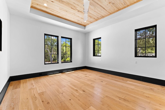 unfurnished room with wooden ceiling, a raised ceiling, baseboards, and wood-type flooring