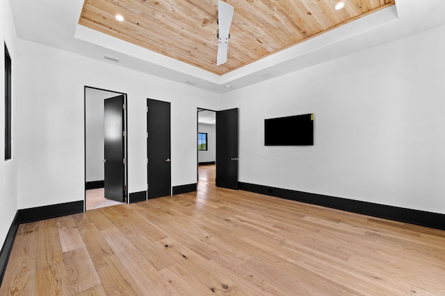 empty room with light wood finished floors, visible vents, wood ceiling, and a tray ceiling