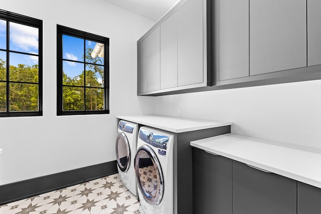 washroom with cabinet space, baseboards, light floors, and washer and clothes dryer