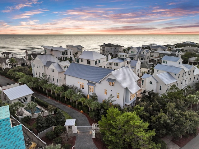 aerial view at dusk featuring a residential view and a water view