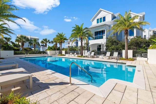 community pool with a patio area and fence