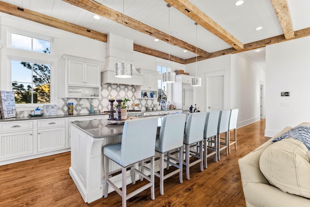 kitchen featuring tasteful backsplash, a kitchen island with sink, a breakfast bar area, and wood finished floors