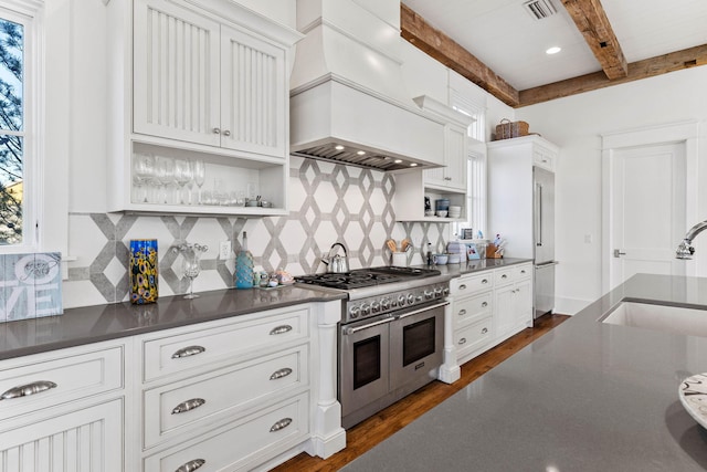 kitchen featuring range with two ovens, dark wood-style floors, dark countertops, a sink, and beamed ceiling