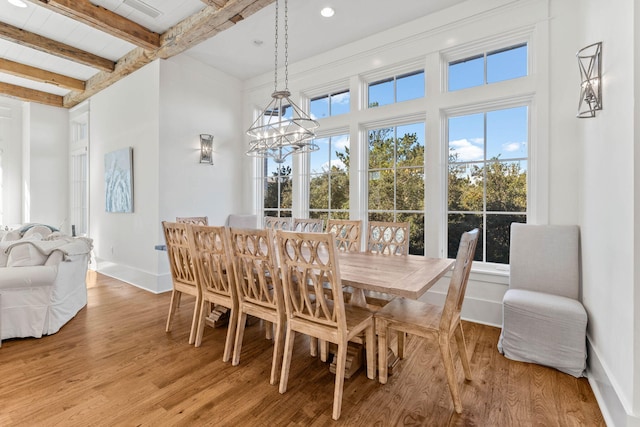 dining area featuring beamed ceiling, light wood-type flooring, a wealth of natural light, and baseboards