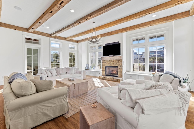 living room featuring beam ceiling, a fireplace, recessed lighting, an inviting chandelier, and wood finished floors