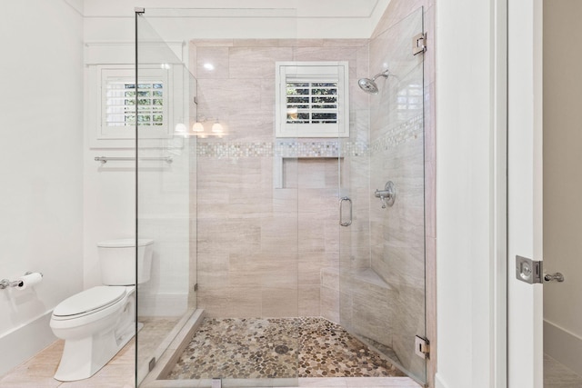 bathroom featuring toilet, tile patterned flooring, a shower stall, and a wealth of natural light