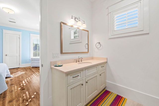 bathroom featuring visible vents, wood finished floors, vanity, and baseboards