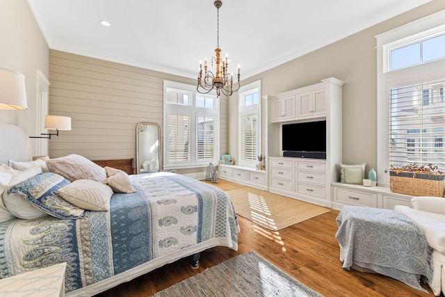 bedroom with a notable chandelier, crown molding, and wood finished floors