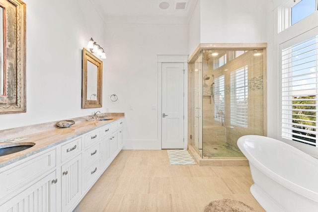 bathroom featuring double vanity, visible vents, a freestanding bath, a shower stall, and a sink