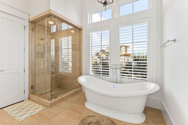 full bathroom with a soaking tub, a shower stall, and baseboards