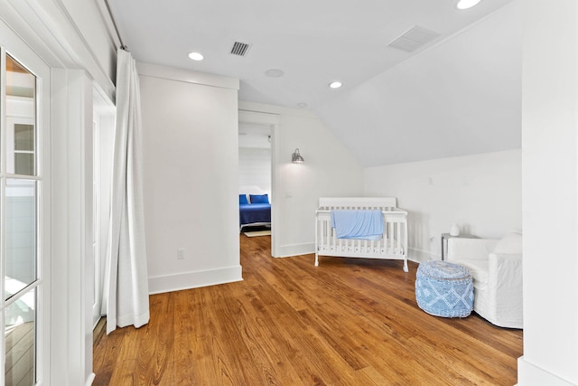 unfurnished bedroom featuring vaulted ceiling, wood finished floors, visible vents, and baseboards