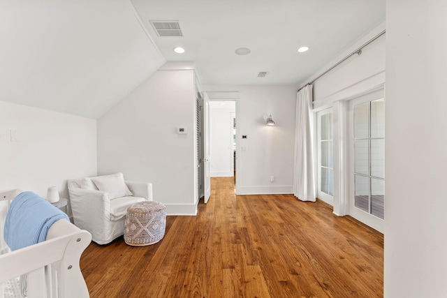 bedroom with vaulted ceiling, wood finished floors, visible vents, and baseboards