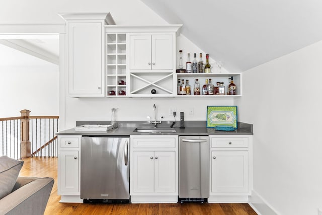 bar with wood finished floors, a sink, stainless steel dishwasher, fridge, and wet bar