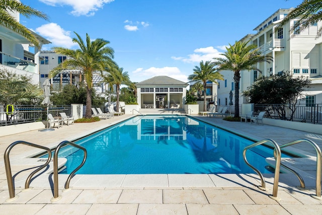 community pool with a patio area and fence