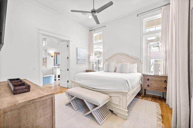 bedroom with ensuite bath, crown molding, multiple windows, and wood finished floors