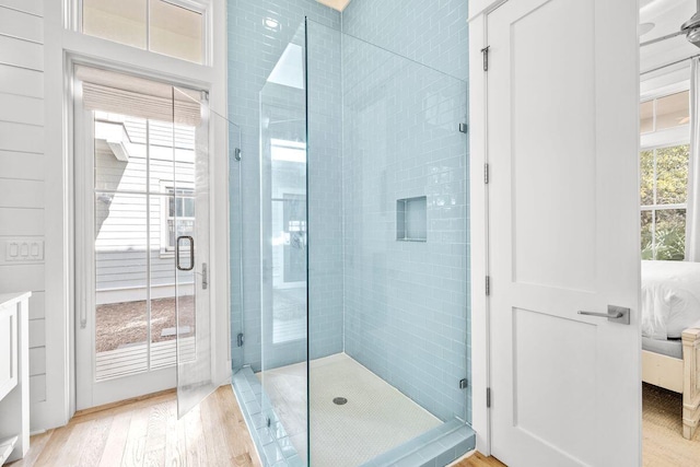 ensuite bathroom featuring a shower stall, wood finished floors, and ensuite bathroom