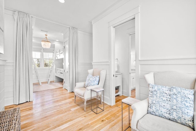 sitting room with recessed lighting, light wood-style flooring, ornamental molding, and a decorative wall