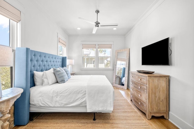 bedroom featuring crown molding, light wood-style flooring, a ceiling fan, and baseboards