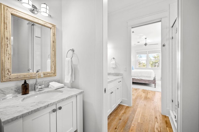 ensuite bathroom featuring vanity, ensuite bath, and wood finished floors