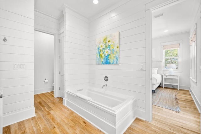 bathroom with wood finished floors, visible vents, ensuite bathroom, a garden tub, and toilet