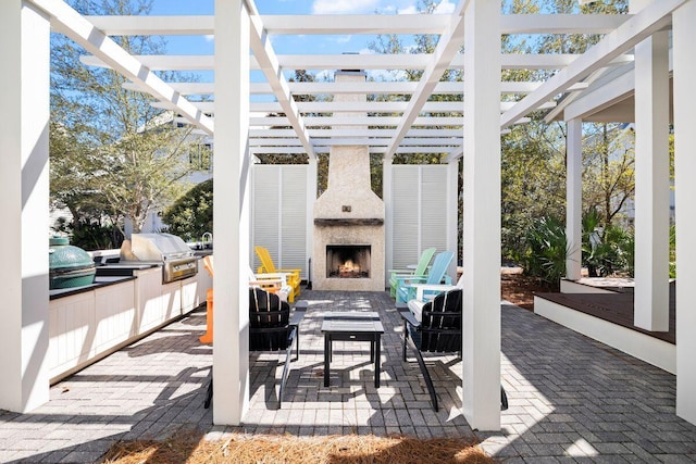 view of patio with area for grilling, a pergola, and a lit fireplace