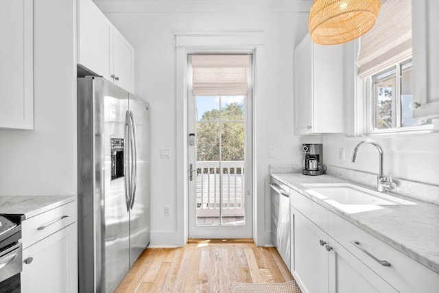 kitchen with a sink, appliances with stainless steel finishes, a healthy amount of sunlight, and white cabinetry