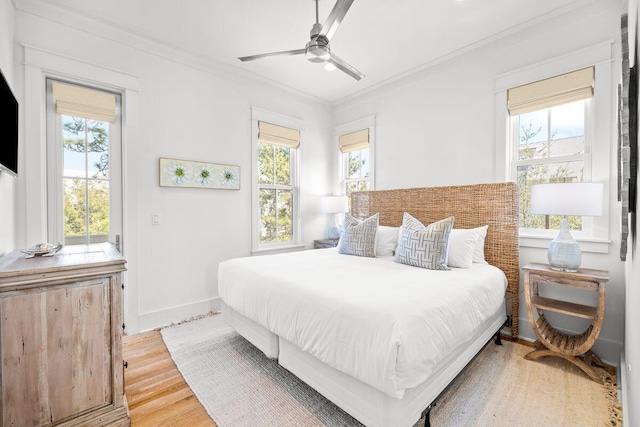 bedroom with multiple windows, light wood-style flooring, baseboards, and ornamental molding