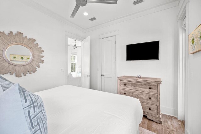 bedroom with crown molding, wood finished floors, visible vents, and ceiling fan