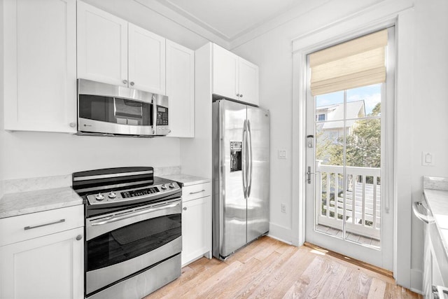 kitchen featuring baseboards, light wood finished floors, stainless steel appliances, white cabinetry, and crown molding