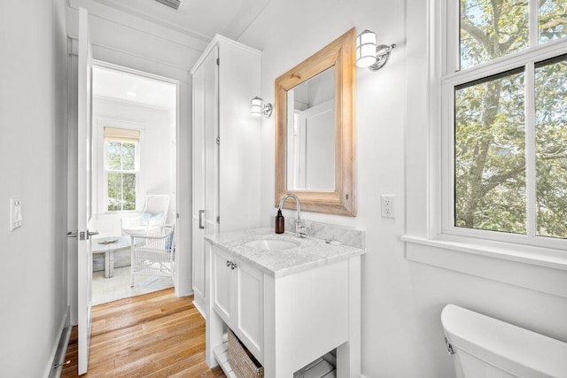 half bath with vanity, toilet, and wood finished floors