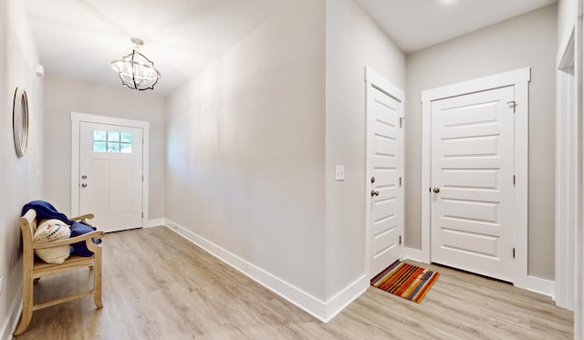 foyer entrance featuring a chandelier, light wood-style floors, and baseboards