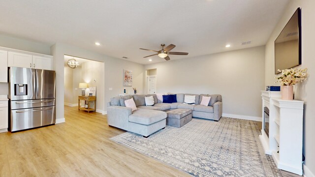 living area featuring a fireplace, light wood finished floors, recessed lighting, visible vents, and baseboards