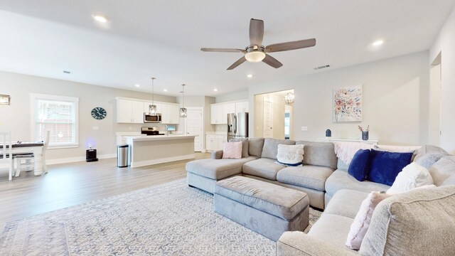 living area featuring recessed lighting, visible vents, baseboards, a ceiling fan, and light wood-style floors