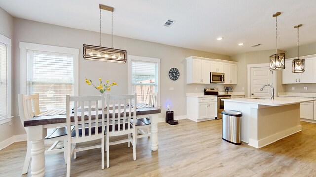 kitchen featuring light countertops, visible vents, appliances with stainless steel finishes, a sink, and light wood-type flooring