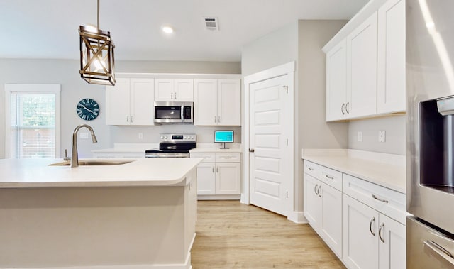 kitchen with stainless steel appliances, a sink, visible vents, light countertops, and light wood-type flooring