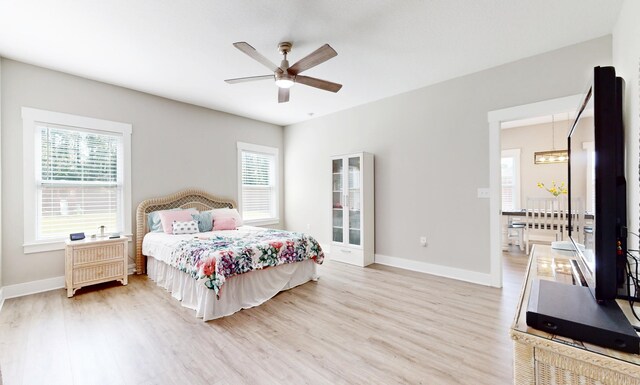 bedroom featuring ceiling fan, multiple windows, light wood-type flooring, and baseboards