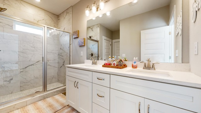 full bathroom with a sink, a marble finish shower, and double vanity